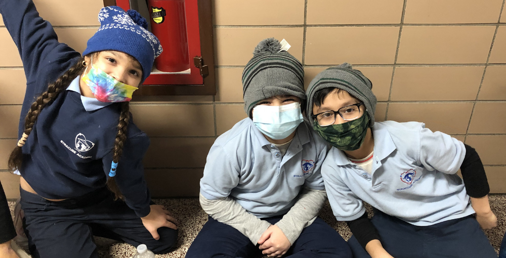 Syracuse Academy of Science and Citizenship elementary school students model their hats and gloves that were donated by Chartwells.